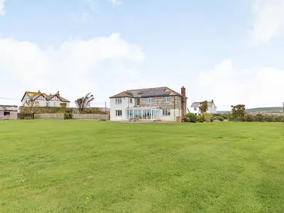 a house with a large field in front of it at Penhallick House in Tintagel