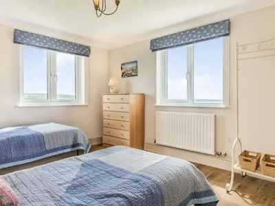 a bedroom with two beds and two windows at Penhallick House in Tintagel