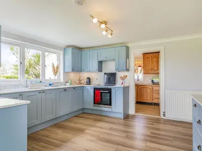 a kitchen with blue cabinets and wooden floors at Penhallick House in Tintagel
