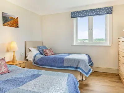 a bedroom with two beds and a window at Penhallick House in Tintagel