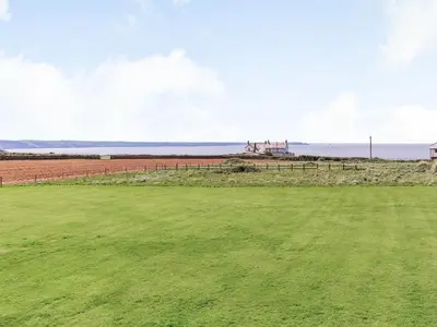 a green field with a farm in the background at Penhallick House in Tintagel