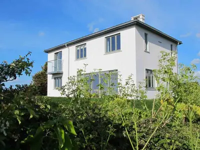 a white house on a hill with bushes at Kareena in Newquay