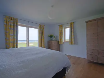 a bedroom with a bed and two windows and a dresser at Kareena in Newquay