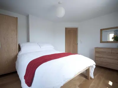 a bedroom with a white bed with a red blanket on it at Kareena in Newquay