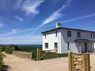 a white house with a gate and a fence at Kareena in Newquay
