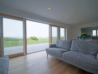 a living room with a couch and large windows at Kareena in Newquay
