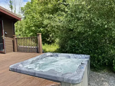 a hot tub sitting on a wooden deck at Willow Lodge in Falmouth