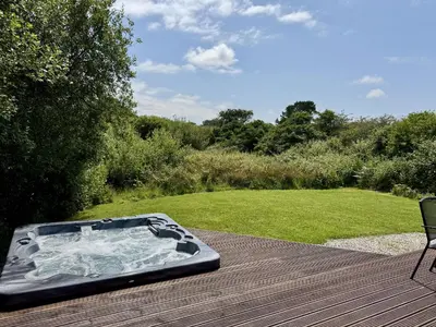 a hot tub sitting on top of a wooden deck at Willow Lodge in Falmouth