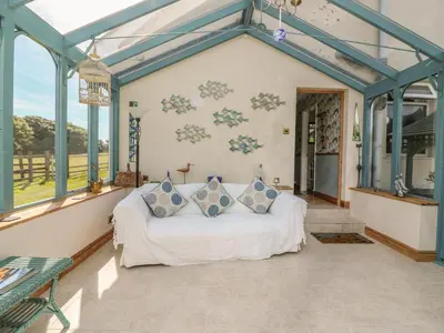 a living room with a white couch in a room with windows at Woolly Welcome in Penzance