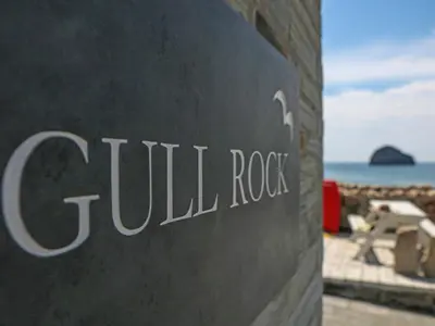 a sign for a hotel near the ocean at Gull Rock in Tintagel