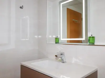 a white bathroom with a sink and a mirror at Seaspell Beach House in Padstow