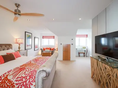 a bedroom with a large bed and a flat screen tv at Seaspell Beach House in Padstow