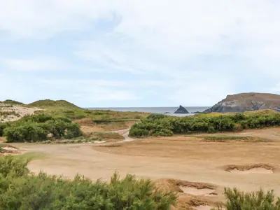 a road in the desert with the ocean in the background at Seaspell Beach House in Padstow