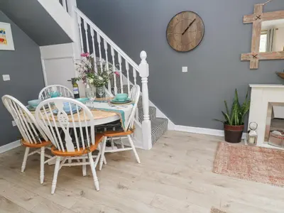 a dining room with a table and chairs and a clock at Tranquility in Falmouth