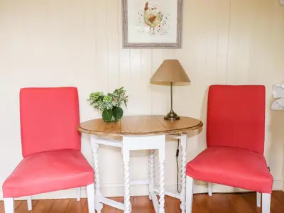two red chairs sitting next to a table with a lamp at Orchard in Wadebridge