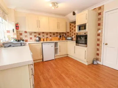 a kitchen with white appliances and a wooden floor at The Chace in Redruth