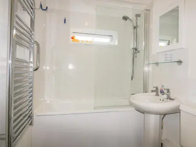 a white bathroom with a shower and a sink at Fistral Surf in Newquay