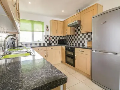 a kitchen with wooden cabinets and a stainless steel refrigerator at Fistral Surf in Newquay