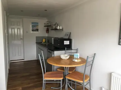 a small kitchen with a wooden table and chairs at Kiki’s Corner in Newquay