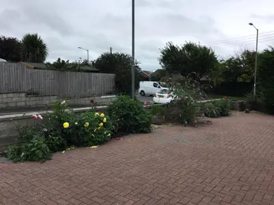 a parking lot with flowers and a white car at Kiki’s Corner in Newquay
