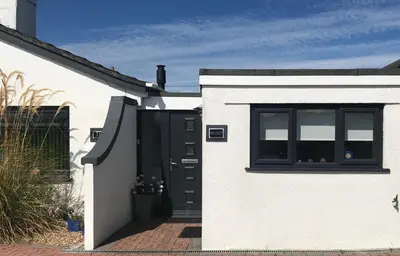 a white house with a black door and a window at Kiki’s Corner in Newquay