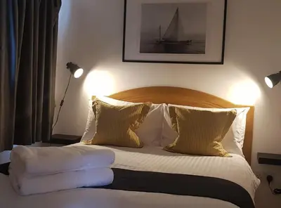 a bedroom with a bed with white sheets and pillows at Little Oaks Chalet - St. Merryn, Padstow in Padstow