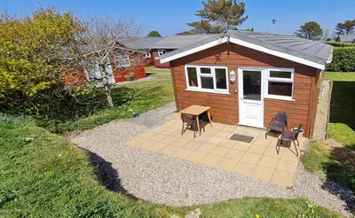 a small cabin with a table and chairs in front of it at Little Oaks Chalet - St. Merryn, Padstow in Padstow