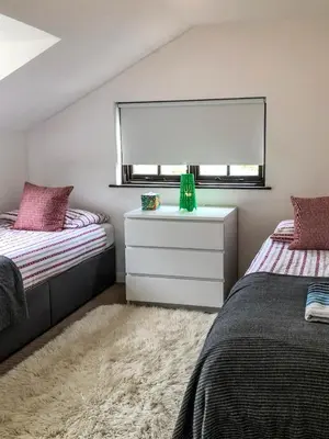 a bedroom with two beds and a dresser and a window at THE OLD RECTORY ROSE COTTAGE in Jacobstow 10 mins to Widemouth bay and Crackington Haven,Nearby Bude,Tintagel,Port Issac,Clovelly,PARKING FOR LARGE AND MULTIPLE VEHICLES in Jacobstow