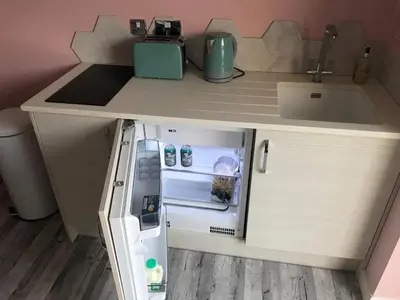 a small refrigerator with its door open next to a sink at Fistral Hideaway in Newquay