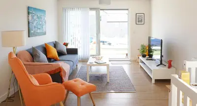 a living room with a blue couch and orange chairs at Stones Throw in Newquay