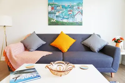 a living room with a blue couch with colorful pillows at Stones Throw in Newquay