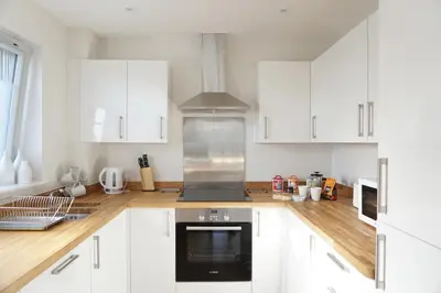 a kitchen with white cabinets and a stove top oven at Stones Throw in Newquay