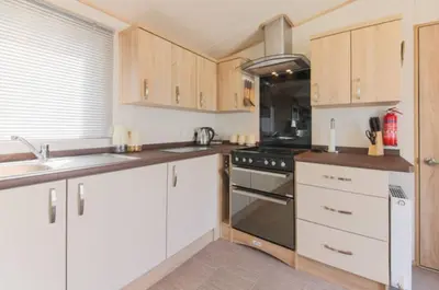 a kitchen with white cabinets and a stove top oven at Blenheim, Padstow in Padstow