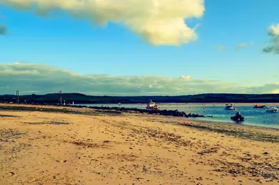 a sandy beach with boats in the water at Blenheim, Padstow in Padstow