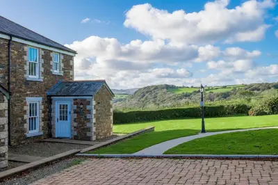 a brick house with a pathway leading to a green field at Green Acres Cottages in Par