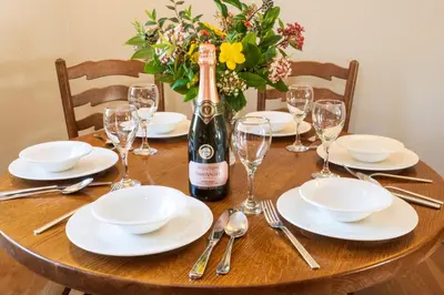 a wooden table with a bottle of wine and glasses at Green Acres Cottages in Par