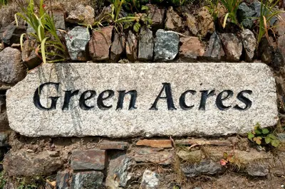 a stone sign that reads green acres on a stone wall at Green Acres Cottages in Par