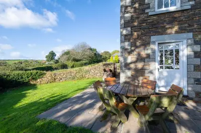 a patio with a table and chairs outside of a building at Green Acres Cottages in Par