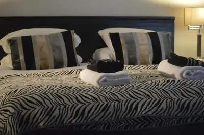 a bed with black and white striped pillows and towels at TOWNHOUSE ROOMS in Truro
