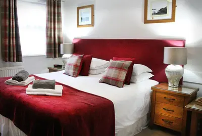 a bedroom with a large bed with a red headboard at TOWNHOUSE ROOMS in Truro