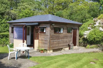 a small wooden cabin with a table in a yard at The Chalet at Mellowvean in St. Agnes