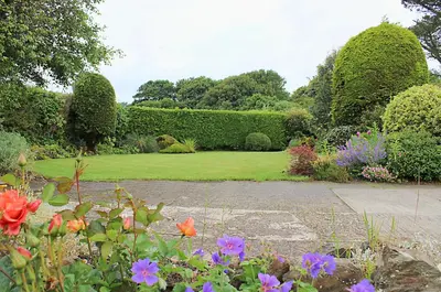 a garden with a lawn with flowers and bushes at The Chalet at Mellowvean in St. Agnes