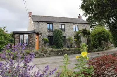 a stone house with flowers in front of it at The Chalet at Mellowvean in St. Agnes