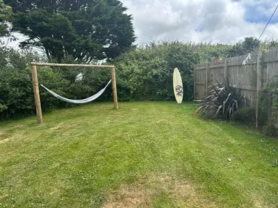 a hammock in a yard next to a fence at Wheal Tor- Beautifully Fitted Wooden Lodge Helston Cornwall in Helston