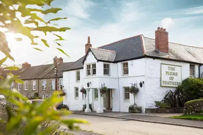 a white building with a sign that reads the thing of excellence at The Plume of Feathers in Mitchell