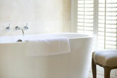 a white bath tub in a bathroom with a stool at The Plume of Feathers in Mitchell