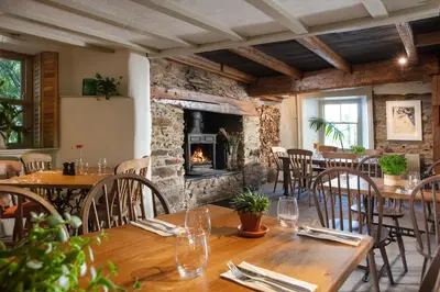 a restaurant with wooden tables and a fireplace at The Plume of Feathers in Mitchell