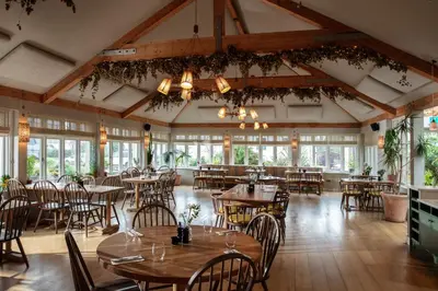 a dining room with tables and chairs and windows at The Plume of Feathers in Mitchell
