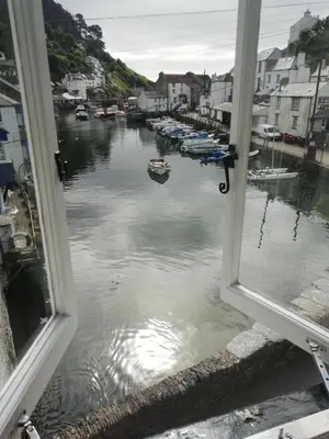 a window with a view of a body of water at The House on the Props in Polperro