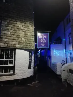 a sign on the side of a building at night at The House on the Props in Polperro
